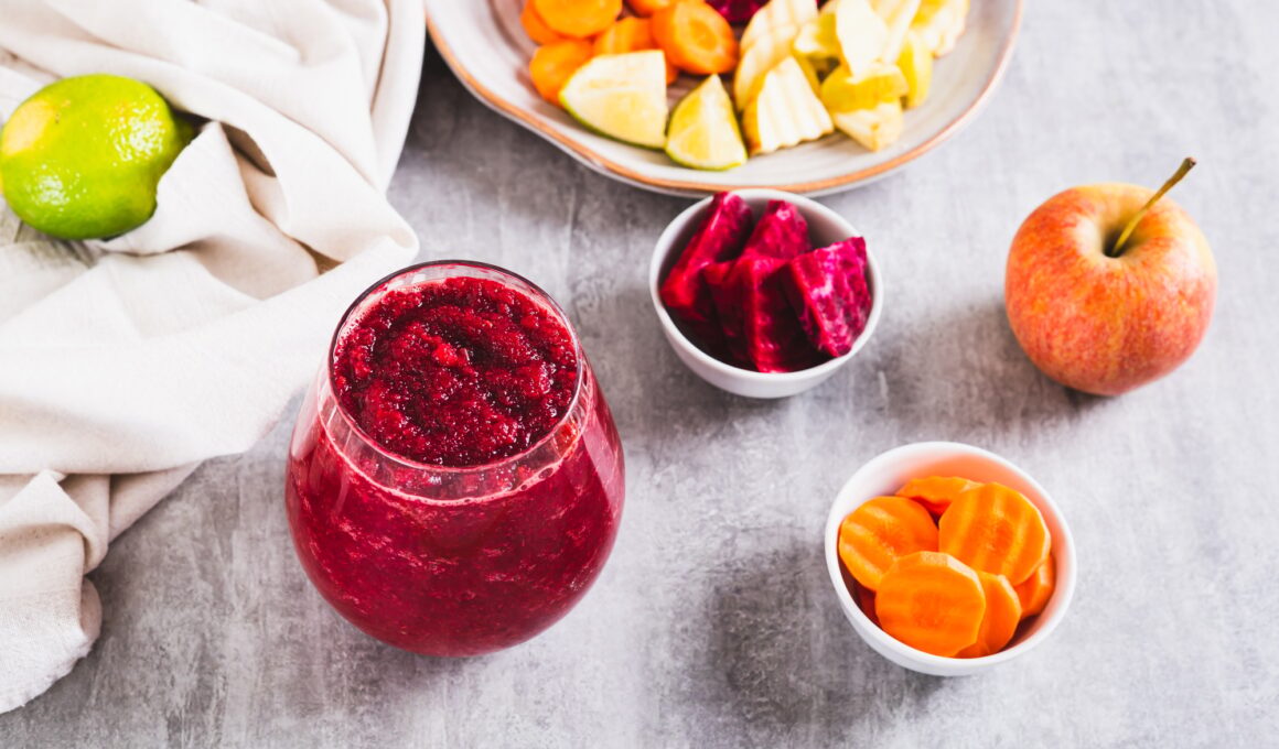 A glass with a mixture of beetroot, apple and carrot juices ABC on the table